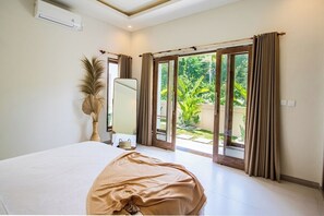 A bedroom with a bed, a mirror, a potted plant, and a sliding glass door leading to a garden. - Amazing Jungle view, 3BDR,  Canggu, huge Pool (Kabupaten Badung)