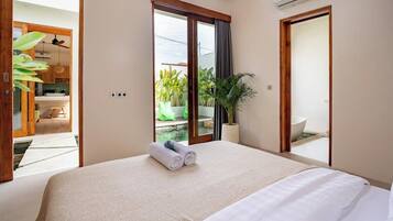 Una habitación de hotel con una cama, una planta en maceta y vistas a un balcón.