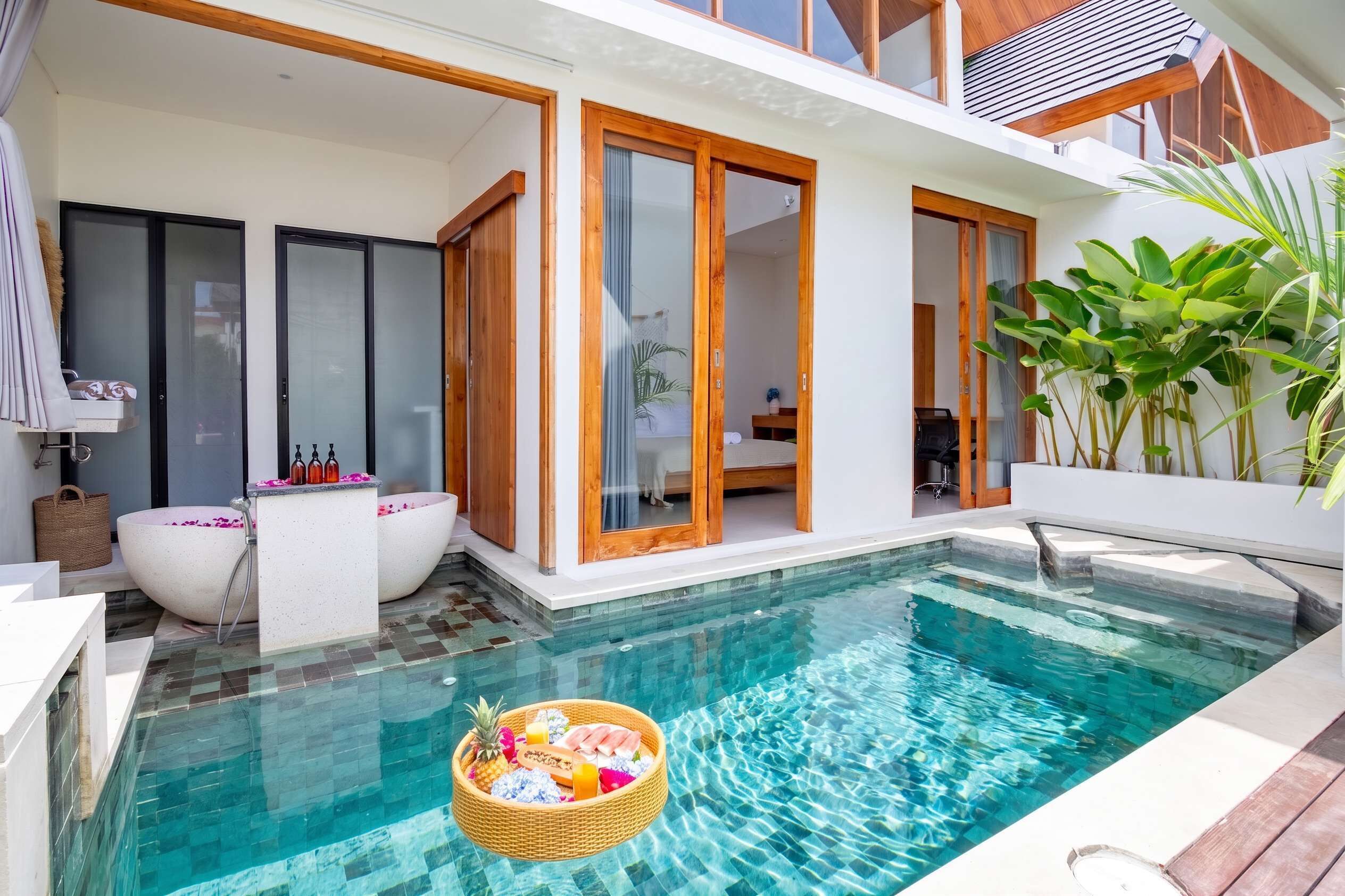 A modern outdoor pool area with a hot tub, a wooden deck, and a glass-enclosed room.