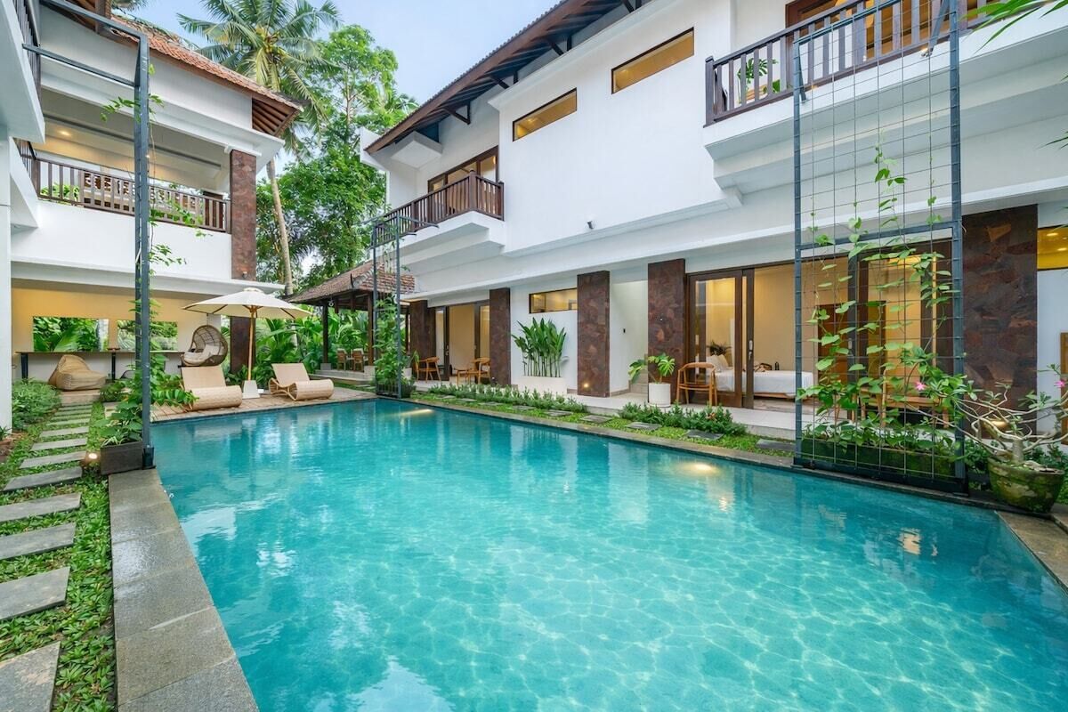 Um hotel moderno com piscina, área de estar ao ar livre e vegetação exuberante.