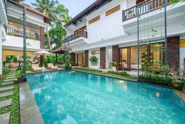 Um hotel moderno com piscina, área de estar ao ar livre e vegetação exuberante.