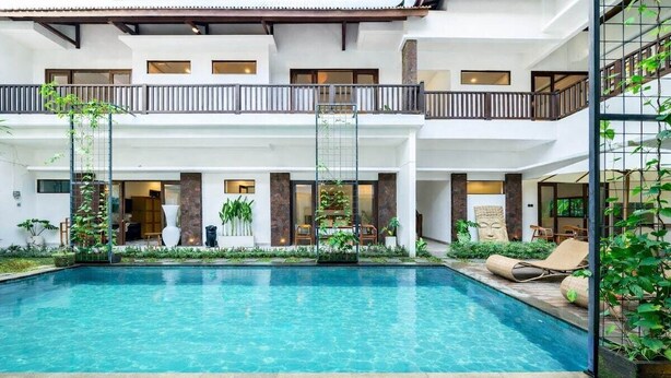 A two-story building with a central courtyard featuring a swimming pool, surrounded by plants and outdoor seating. - Boutique 1BR in Central Ubud w Pool, Patio&Balcony (Gianyar Regency)