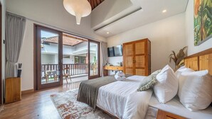 A bedroom with a bed, a wooden wardrobe, a TV, and a balcony with a view of the outside. - Boutique 1BR in Central Ubud w Pool, Patio&Balcony (Gianyar Regency)