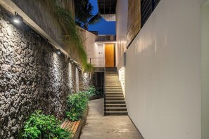 A narrow outdoor corridor with a stone wall on one side and a staircase leading to an upper level. - Hidden 3BR Ubud Oasis w Pool & Open-Plan Living (Gianyar Regency)