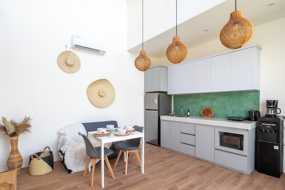 A modern kitchen with white cabinets, a green backsplash, and a coffee machine.