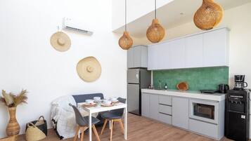 A modern kitchen with white cabinets, a green backsplash, and a coffee machine.