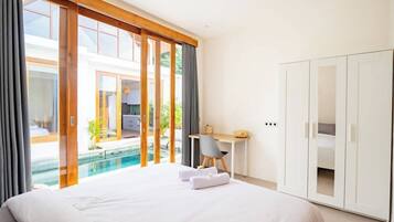 Una habitación de hotel con cama, escritorio y vistas a una piscina.