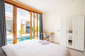 Et hotelværelse med seng, skrivebord og udsigt til en swimmingpool.