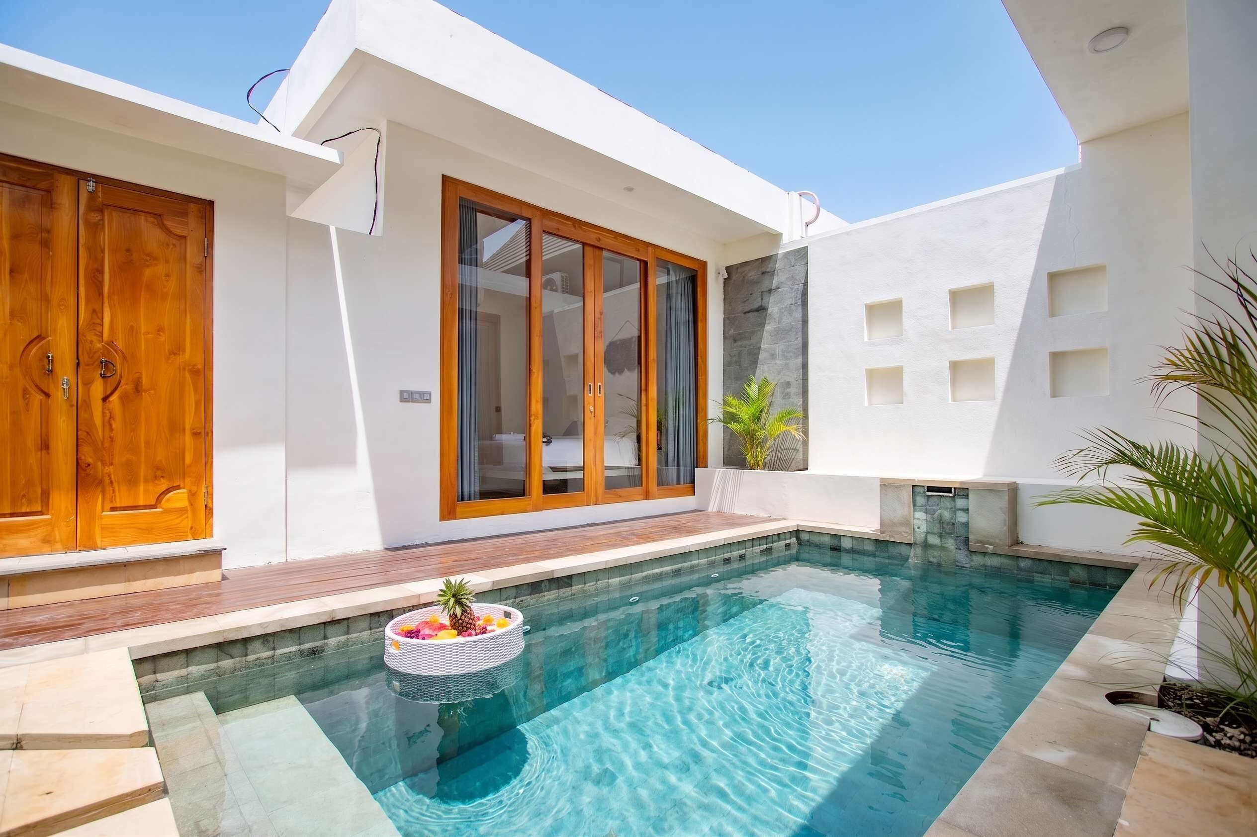 A modern house with a swimming pool, wooden doors, and a large sliding glass door.