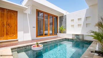 A modern house with a swimming pool, wooden doors, and a large sliding glass door.