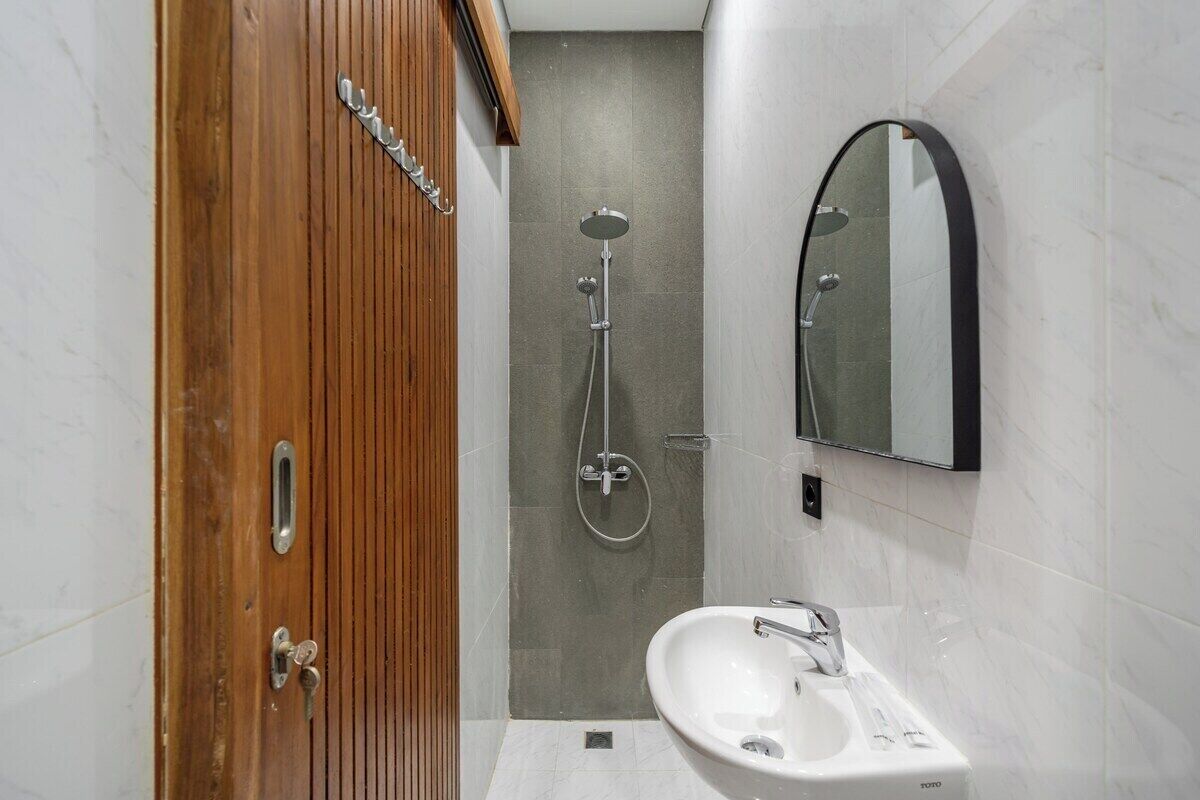 Une salle de bain avec une porte en bois, une douche, un lavabo et un miroir.