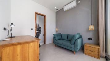 Ein modernes Wohnzimmer mit einem Holztisch, einem blaugrünen Sofa und einem kleinen Nachttisch.