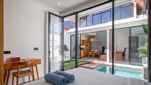 Une chambre moderne avec un grand lit, un bureau et une vue sur une piscine et une cuisine.