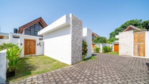 Un quartier résidentiel moderne avec une allée pavée, des murs blancs et des portes en bois.