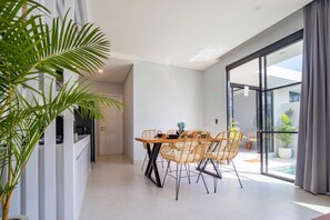 Ein moderner Essbereich mit Glastrennwand, einem Holztisch und Korbstühlen.