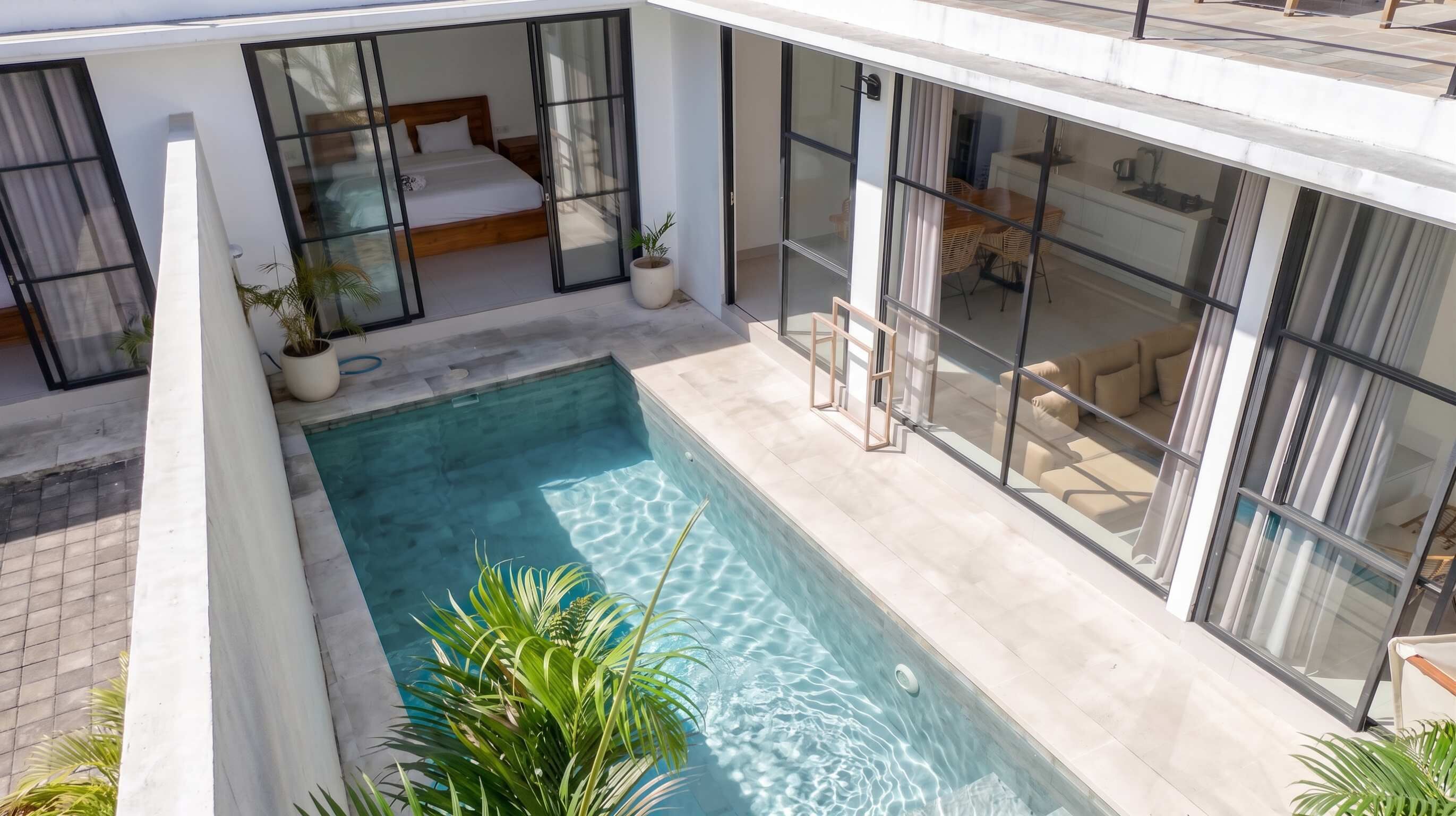 Et moderne hus med swimmingpool, store glasvinduer og en velholdt have.