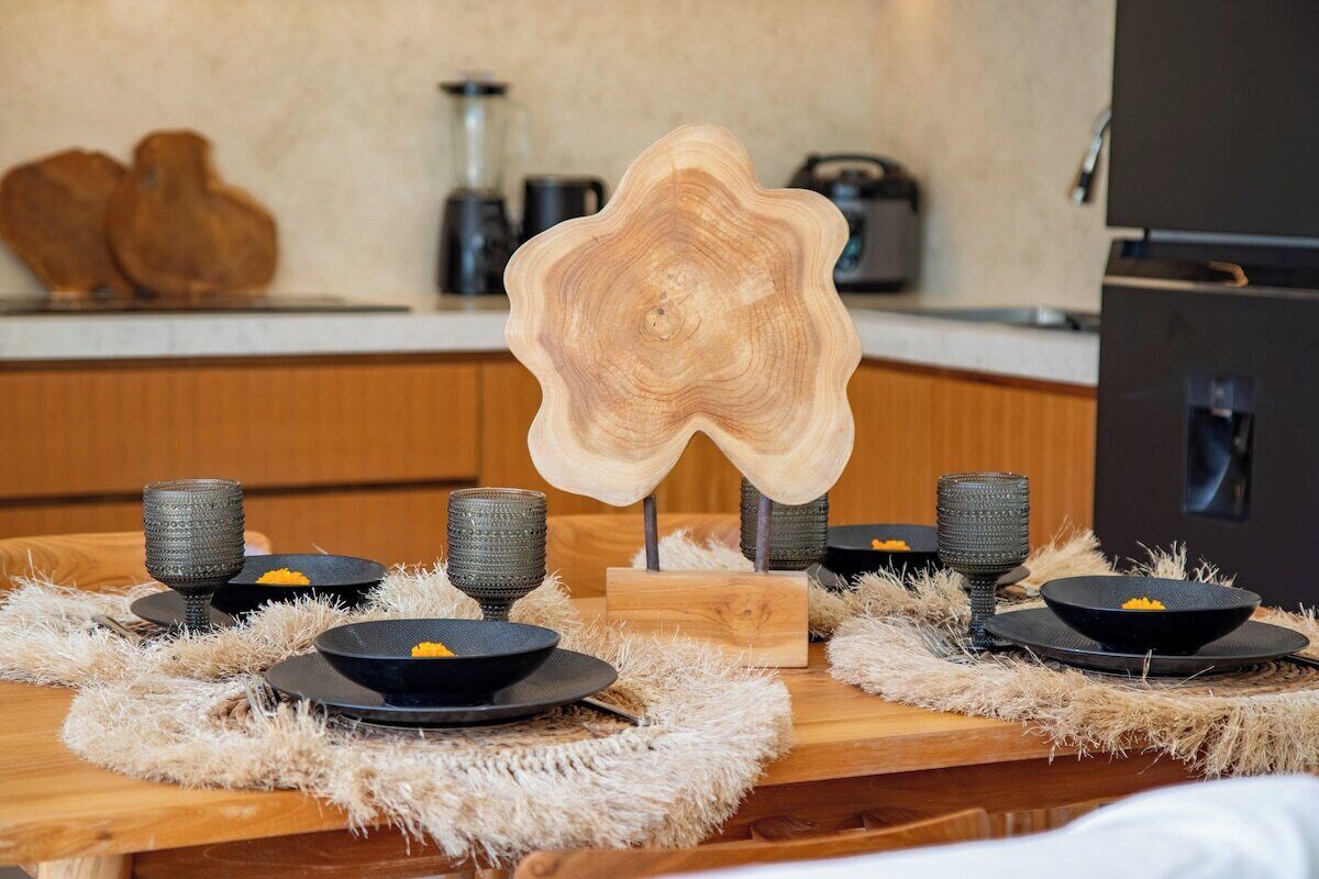 Una mesa de comedor con un centro de mesa original, platos negros y copas con textura.