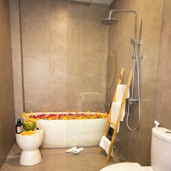 Ein Badezimmer mit Badewanne, Dusche, Toilette und einem Holzstuhl.