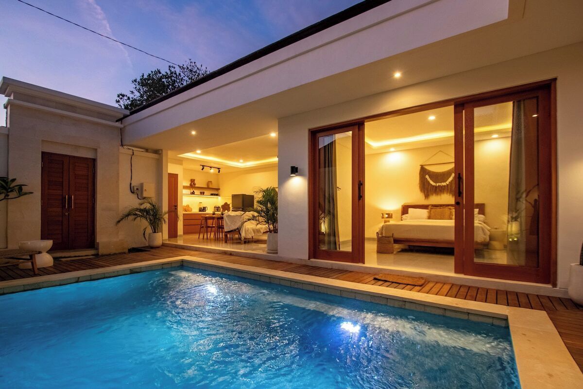 A modern house with a swimming pool, a dining area, and a bedroom with a sliding glass door.