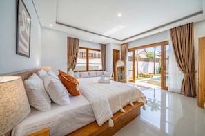Ein Hotelzimmer mit einem großen Bett, einer Sitzecke und Blick auf einen Pool und Außenbereich.