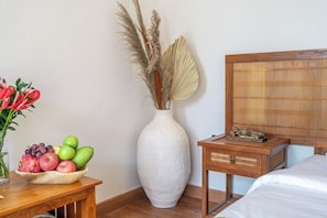 A room with a bed, a bedside table with a lamp, a vase with dried plants, and a bowl of fruit. - Chic 1BR in Top Ubud's Spot w Spacious Pool+Garden (Gianyar Regency)