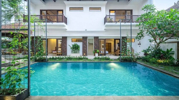 Uma casa de dois andares com piscina na frente.