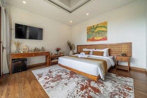 A bedroom with a bed, a desk, a television, and a painting on the wall. - Chic 1BR in Top Ubud's Spot w Spacious Pool+Garden (Gianyar Regency)