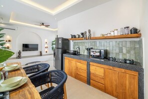 Eine moderne Küche mit Essbereich, ausgestattet mit Backofen, Kühlschrank und verschiedenen Küchenutensilien auf der Arbeitsplatte.