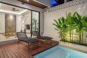 Ein Poolbereich mit zwei Liegestühlen, einem Deckenventilator und einem großen Fenster.