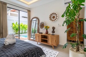 Ein Schlafzimmer mit einem Bett, einem Holzschrank, einem Spiegel und einer Zimmerpflanze.