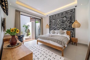 Ein modernes Schlafzimmer mit Bett, Nachttischen, einem großen Wandbild und Blick durch eine Glastür.