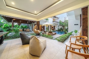 A modern outdoor lounge area with seating, a pool, and lush greenery. - Cozy 1BR w Spacious Pool+Garden • Ubud's Best Spot (Gianyar Regency)