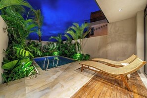 Ein Poolbereich mit Liegestühlen und tropischer Bepflanzung.