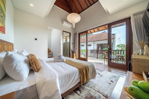 Ein Schlafzimmer mit einem großen Bett, Holzboden, einem Balkon mit Aussicht und einem Tisch mit Obst.