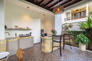 Un espace cuisine extérieur doté d’un plan de travail en pierre, de deux chaises, d’un luminaire suspendu et d’une plante en pot.
