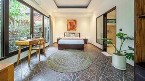 Une chambre à coucher avec un lit, un bureau, une chaise, une grande fenêtre et une plante en pot.