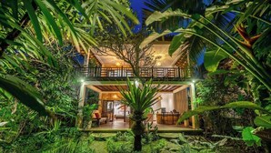 Un bâtiment à deux étages doté d’un balcon, entouré d’une végétation luxuriante.