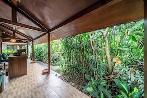 A covered outdoor area with a wooden floor, surrounded by lush tropical vegetation. - New 3BR Villa in Serene Ubud Complex w Spa+2 Pools (Kabupaten Gianyar)