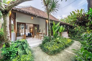 A house with a tiled roof, a covered porch, and a garden with various plants. - Tranquil 1BR Hideaway in Central Ubud w Pool+Patio (Kabupaten Gianyar)