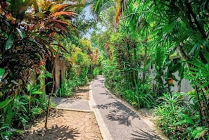 A narrow pathway flanked by lush greenery and a white building. - Tranquil 1BR Hideaway in Central Ubud w Pool+Patio (Kabupaten Gianyar)