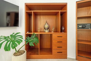 Ein Holzschrank mit mehreren Fächern, ein an der Wand befestigter Fernseher und ein Blumentopf.