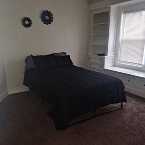 A bedroom with a bed, a window with blinds, a dresser, and two wall decorations. - Lovely 2-bedroom apartment with AC in vibrant Cleveland (Cleveland)