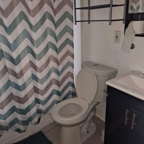 A bathroom with a toilet, a sink, and a shower curtain with a zigzag pattern. - Lovely 2-bedroom apartment with AC in vibrant Cleveland (Cleveland)