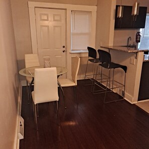 A dining area with a glass table and chairs, a door, and a window with blinds. - Lovely 2-bedroom apartment with AC in vibrant Cleveland (Cleveland)