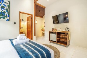 Ein Hotelzimmer mit einem Bett, einem Fernseher, einem Schreibtisch mit Wasserkocher und einem Bild an der Wand.