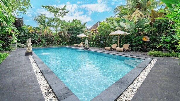 A rectangular swimming pool with clear water, surrounded by a stone border and a pebble edge. There are lounge chairs and umbrellas near the pool, and lush greenery surrounds the area. - Cozy 1BR Stay w Pool, Garden & Patio, Central Ubud (Kabupaten Gianyar)