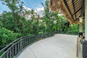 Un sentier sinueux bordé d’une rambarde métallique, entouré d’une végétation tropicale luxuriante et de palmiers.