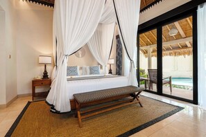 Ein Schlafzimmer mit Baldachinbett, einer Bank, einem Nachttisch, einer Lampe und Blick auf einen Außenpoolbereich.