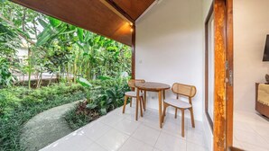 Un pati amb taula i cadires, envoltat de vegetació exuberant i vistes a un jardí.