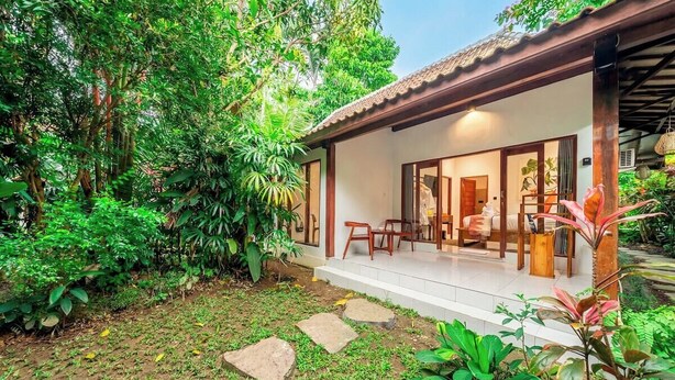 Una casa amb un porxo cobert, un jardí amb pedres i diverses plantes.